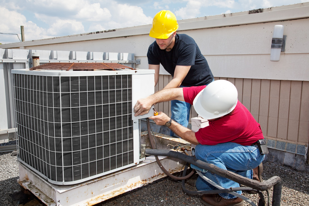 Two workers keeping an air conditioning unit properly maintained.