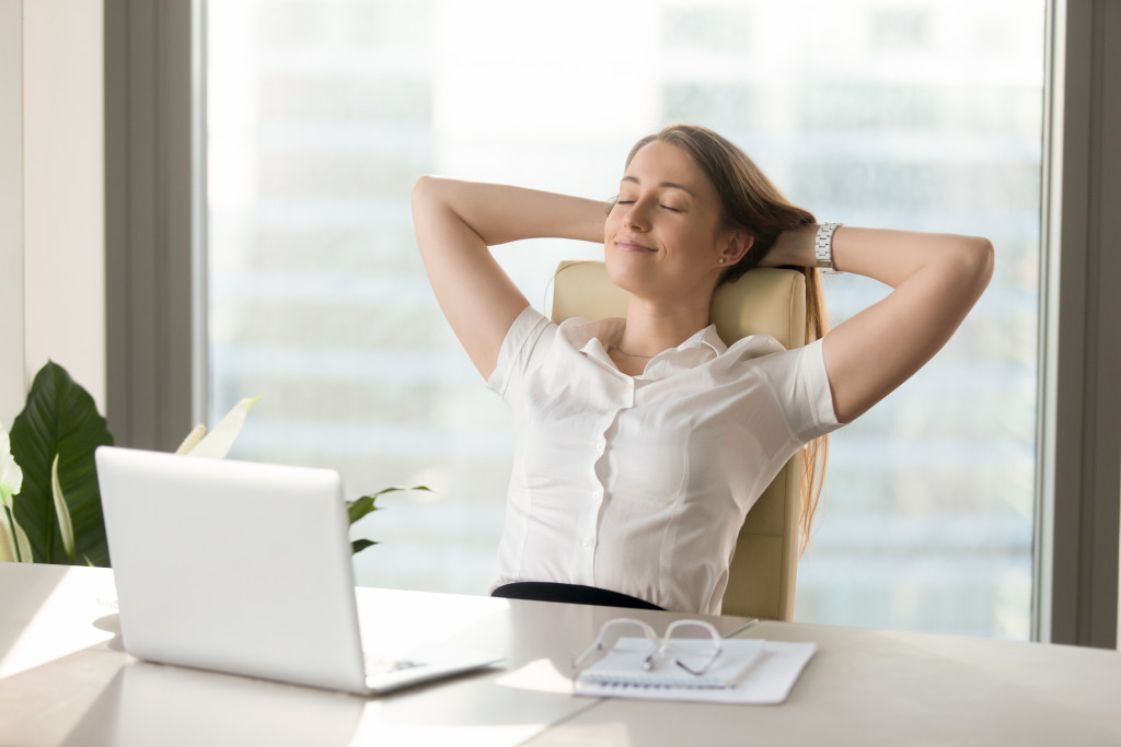 smiling businesswoman relaxed in office with her arms on her head