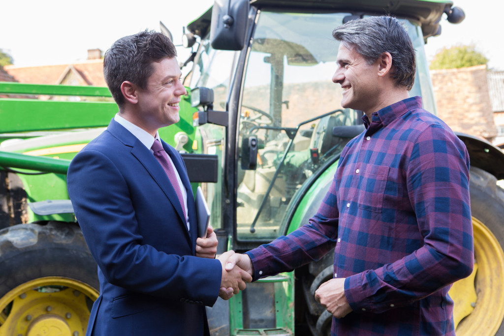 a male farming shaking hands to a businessman
