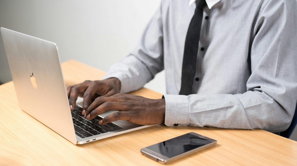 professionally dressed man typing on a laptop