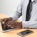 professionally dressed man typing on a laptop