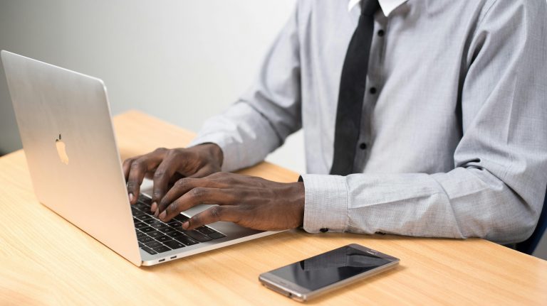 professionally dressed man typing on a laptop