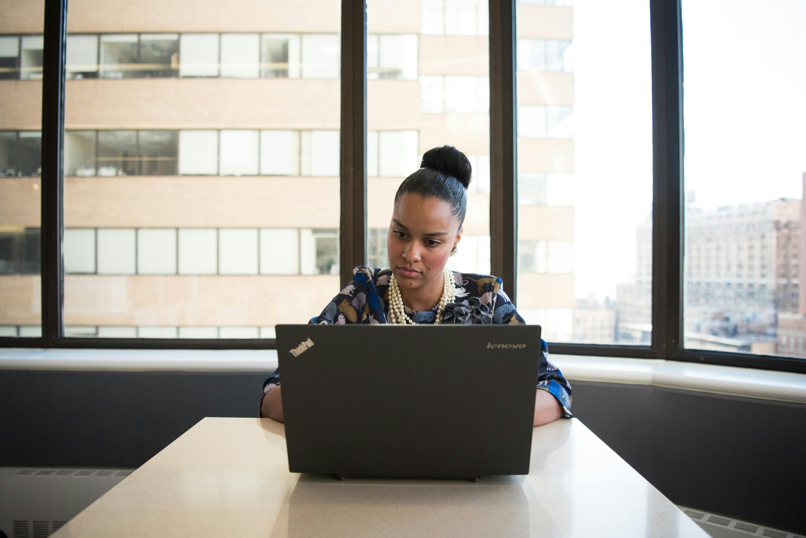 professionally dressed woman typing on a laptop in an office